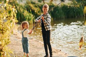 se divertindo. menino com sua irmã na pesca ao ar livre no verão juntos foto