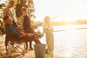 natureza bela. pai e mãe com filho e filha pescando juntos ao ar livre no verão foto