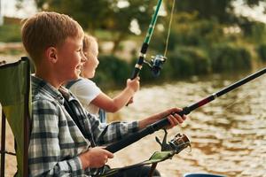 lago de tamanho médio. menino com sua irmã na pesca ao ar livre no verão juntos foto