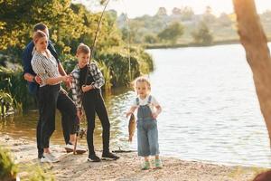 lago de tamanho médio. pai e mãe com filho e filha pescando juntos ao ar livre no verão foto