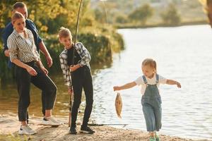 Atividades de final de semana. pai e mãe com filho e filha pescando juntos ao ar livre no verão foto