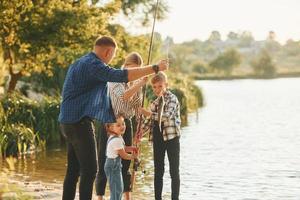 Atividades de final de semana. pai e mãe com filho e filha pescando juntos ao ar livre no verão foto