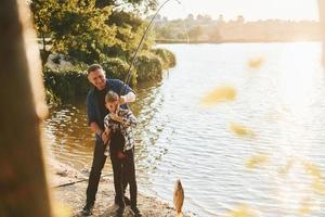 alguma comida para comer. pai e filho pescando juntos ao ar livre no verão foto