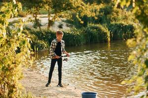 com boas capturas. menino em roupas casuais na pesca ao ar livre no verão foto