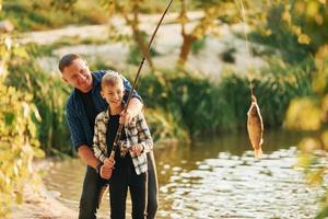 pai e filho pescando juntos ao ar livre no verão foto