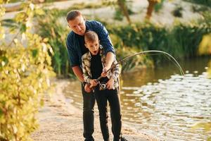 segurando a captura. pai e filho pescando juntos ao ar livre no verão foto