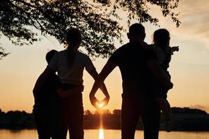 olhando o pôr do sol. família de mãe, pai e filhos está no acampamento foto