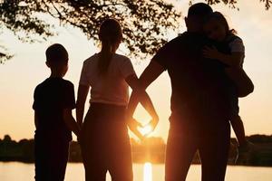 olhando o pôr do sol. família de mãe, pai e filhos está no acampamento foto