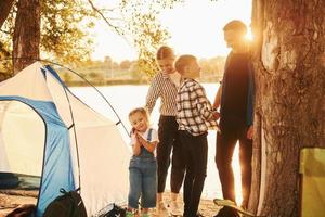 bela luz do sol. família de mãe, pai e filhos está no acampamento foto