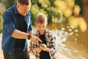 segurando a captura. pai e filho pescando juntos ao ar livre no verão foto