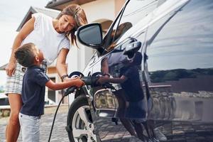 carregando o carro. mulher com menino perto do automóvel moderno durante o dia foto