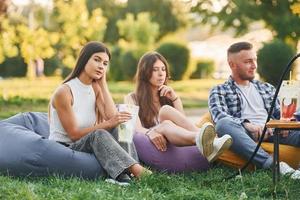 em roupas casuais. grupo de jovens tem uma festa no parque durante o dia de verão foto