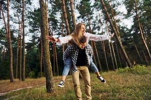 mulher está montando seu homem. casal feliz está ao ar livre na floresta durante o dia foto