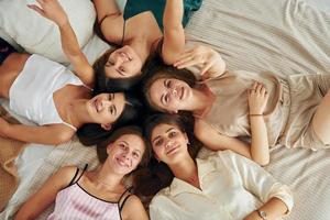 descansando na cama. grupo de mulheres felizes que está em uma despedida de solteira foto