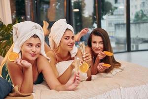 deitada na cama com rodelas de laranja. grupo de mulheres felizes que está em uma despedida de solteira foto