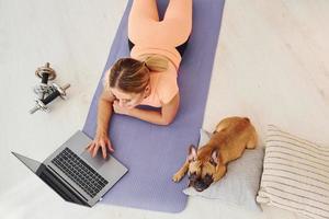 vista superior da mulher com cachorro pug e laptop que está em casa durante o dia foto