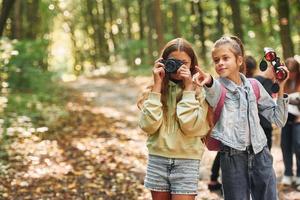 vista frontal das crianças que está na floresta verde no dia de verão juntos foto