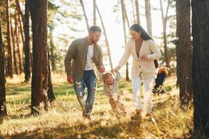 dando um passeio. família feliz de pai, mãe e filha está na floresta foto