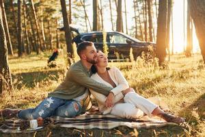 casal feliz sentado no chão da floresta foto