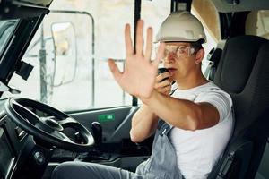 motorista está no trabalho. homem de uniforme profissional está no poço emprestado durante o dia foto