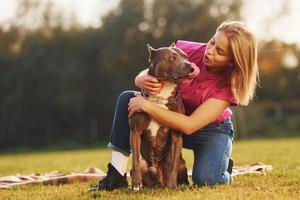 amizade entre humanos e animais. mulher em roupas casuais está com pit bull ao ar livre foto