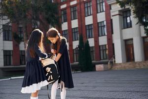 concepção de amizade. duas alunas estão do lado de fora juntas perto do prédio da escola foto