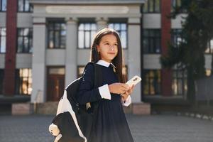 aluna está do lado de fora perto do prédio da escola foto