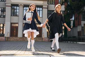 duas alunas estão correndo juntas perto do prédio da escola foto