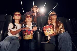 vista frontal. grupo de crianças sentadas no cinema e assistindo filme juntos foto