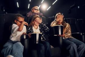 comendo pipoca. grupo de crianças sentadas no cinema e assistindo filme juntos foto