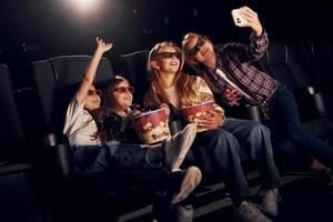 fazendo selfie. grupo de crianças sentadas no cinema e assistindo filme juntos foto