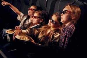 em óculos 3d. grupo de crianças sentadas no cinema e assistindo filme juntos foto