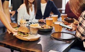 sentado e descansando. grupo de jovens amigos juntos no bar com cerveja foto