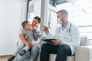 o menino está sendo examinado. dois médicos de jaleco branco estão na clínica trabalhando juntos foto