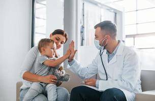 ajudando a criança. dois médicos de jaleco branco estão na clínica trabalhando juntos foto