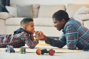 vista lateral. pai afro-americano com seu filho em casa foto
