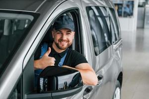 com veículo. entregador de uniforme está dentro de casa com carro e com pedido foto