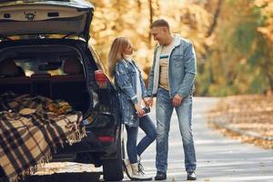 casal dançando na estrada no parque perto de automóvel foto