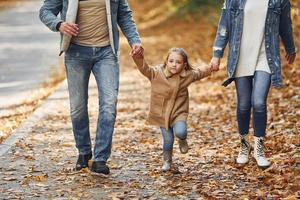 segurando a filha pelas mãos. família feliz está no parque no outono juntos foto
