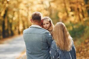 menina com seus pais. família feliz está no parque no outono juntos foto