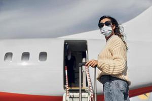 jovem passageira em roupas casuais está ao ar livre perto do avião foto