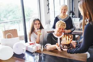 mulher sênior com família e amigos comemorando um aniversário dentro de casa foto