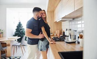 manhã para o jovem casal que está dentro de casa na cozinha foto