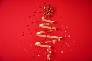 árvore de natal feita de fita festiva e confete em um fundo vermelho foto