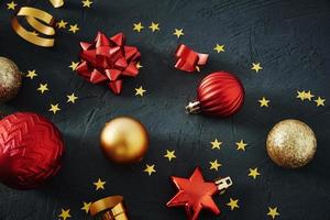 enfeites de natal vermelhos e dourados e fitas festivas em fundo escuro foto