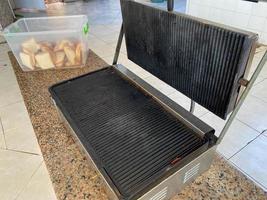 grande grelha de ferro preto para fritar comida de carne na cozinha da cantina do restaurante de fast food da lanchonete foto