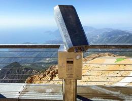 binóculos em uma plataforma de observação feita de metal cinza e denso. passeio panorâmico, observação da vista das montanhas para baixo. a beleza de um país tropical foto