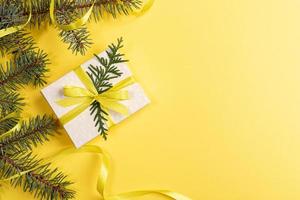 natal, ano novo, fundo amarelo dos namorados com caixa de presente diy e ramos de abeto verde decorados com fita amarela. foto