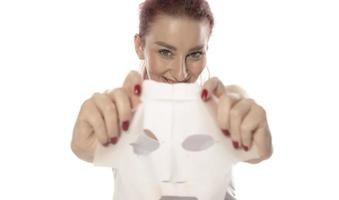 cuidados faciais e tratamentos de beleza. mulher com uma máscara hidratante de folha no rosto isolada no fundo branco foto