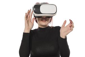 mulher muito bonita animada no fone de ouvido vr olhando para cima e tentando tocar objetos na realidade virtual foto